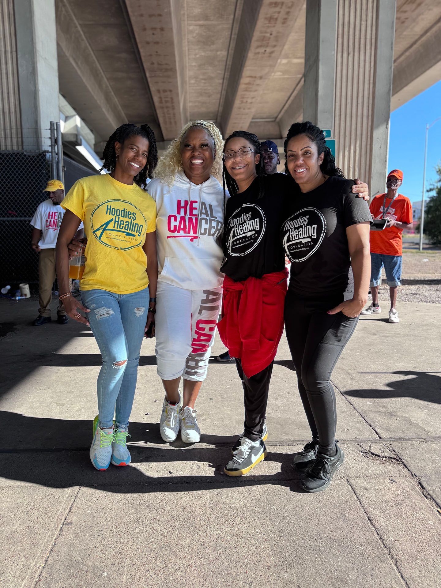 A group of women are posing for a picture under a bridge.