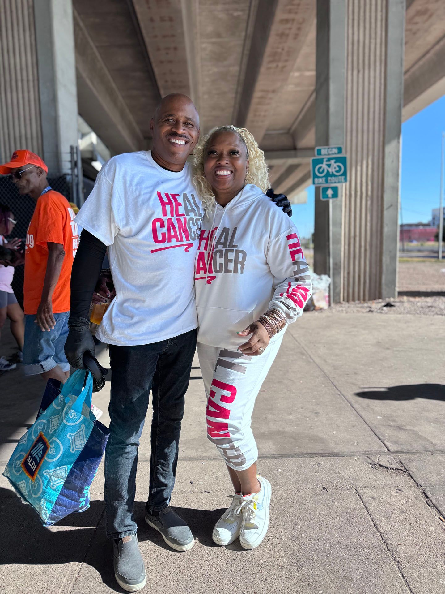 A man and a woman are posing for a picture under a bridge.