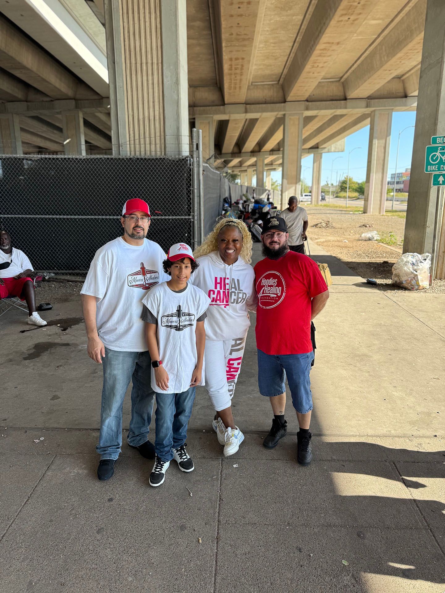 A group of people are posing for a picture under a bridge.
