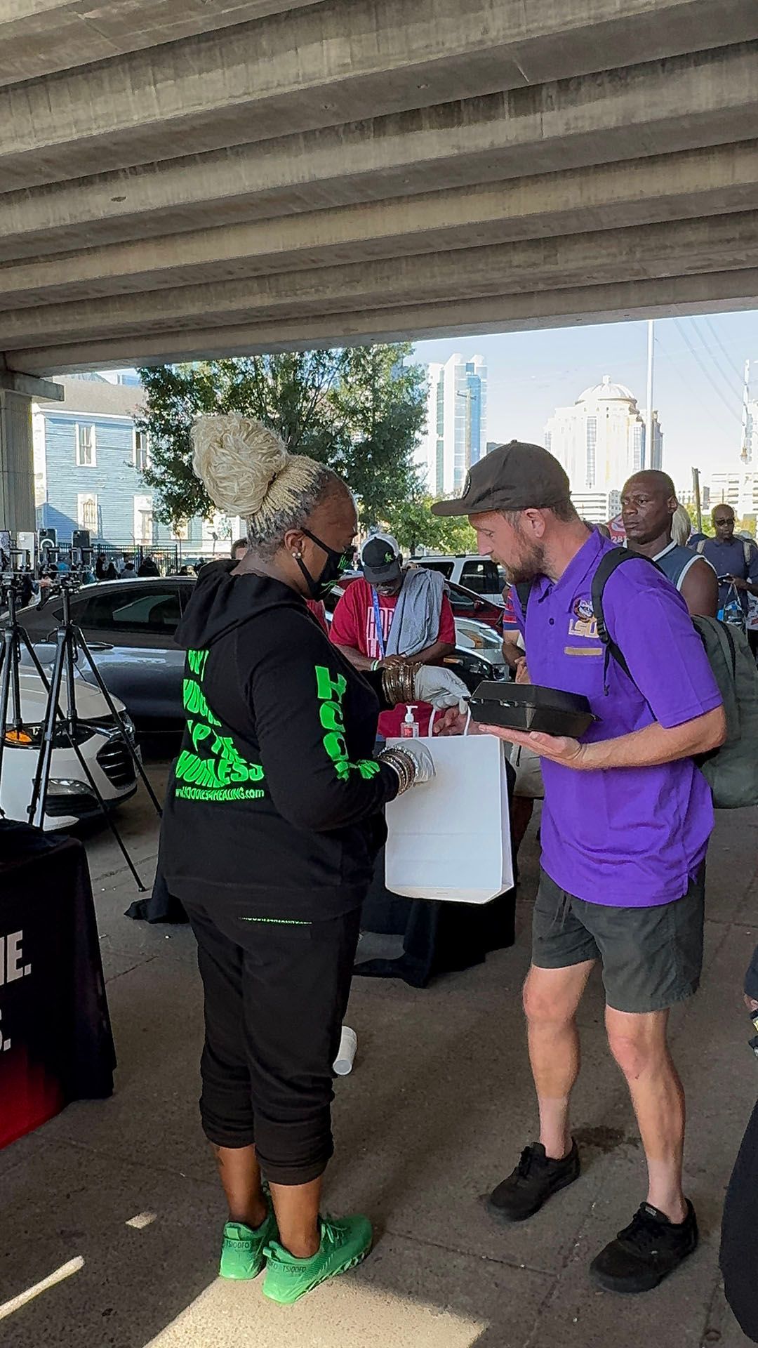 A man in a purple shirt is talking to a woman in a black hoodie.