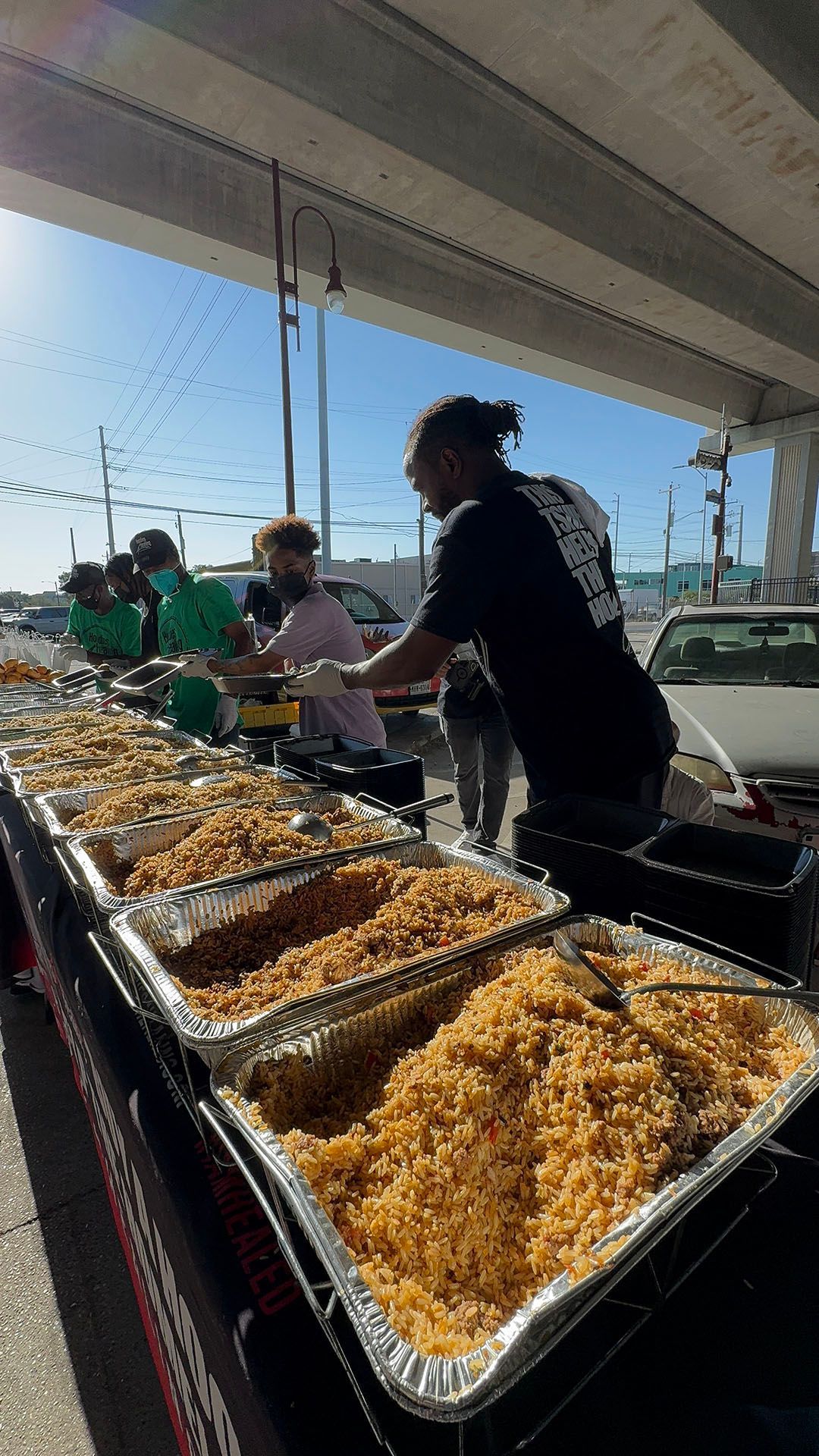 A man is standing in front of a table filled with trays of food.