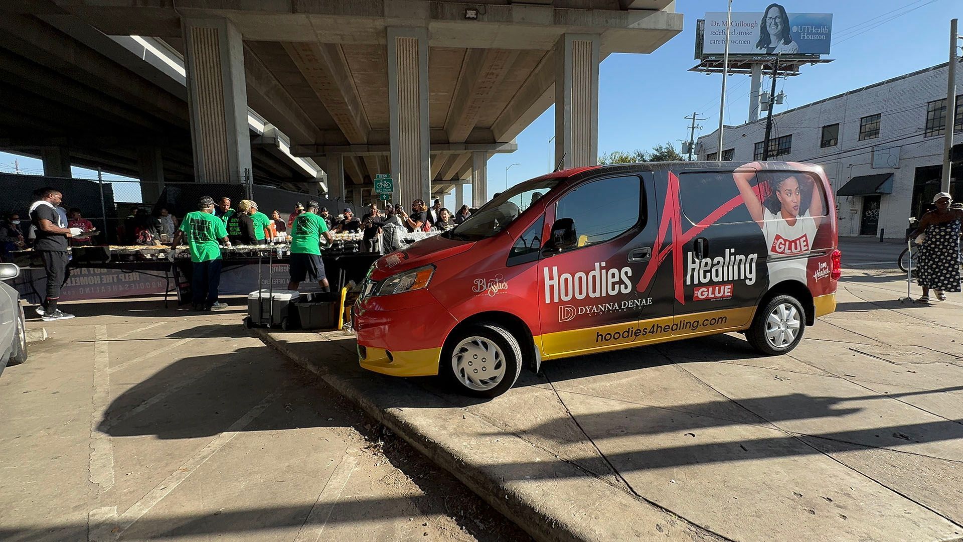 A red van with the word hoodies on the side is parked on the side of the road.