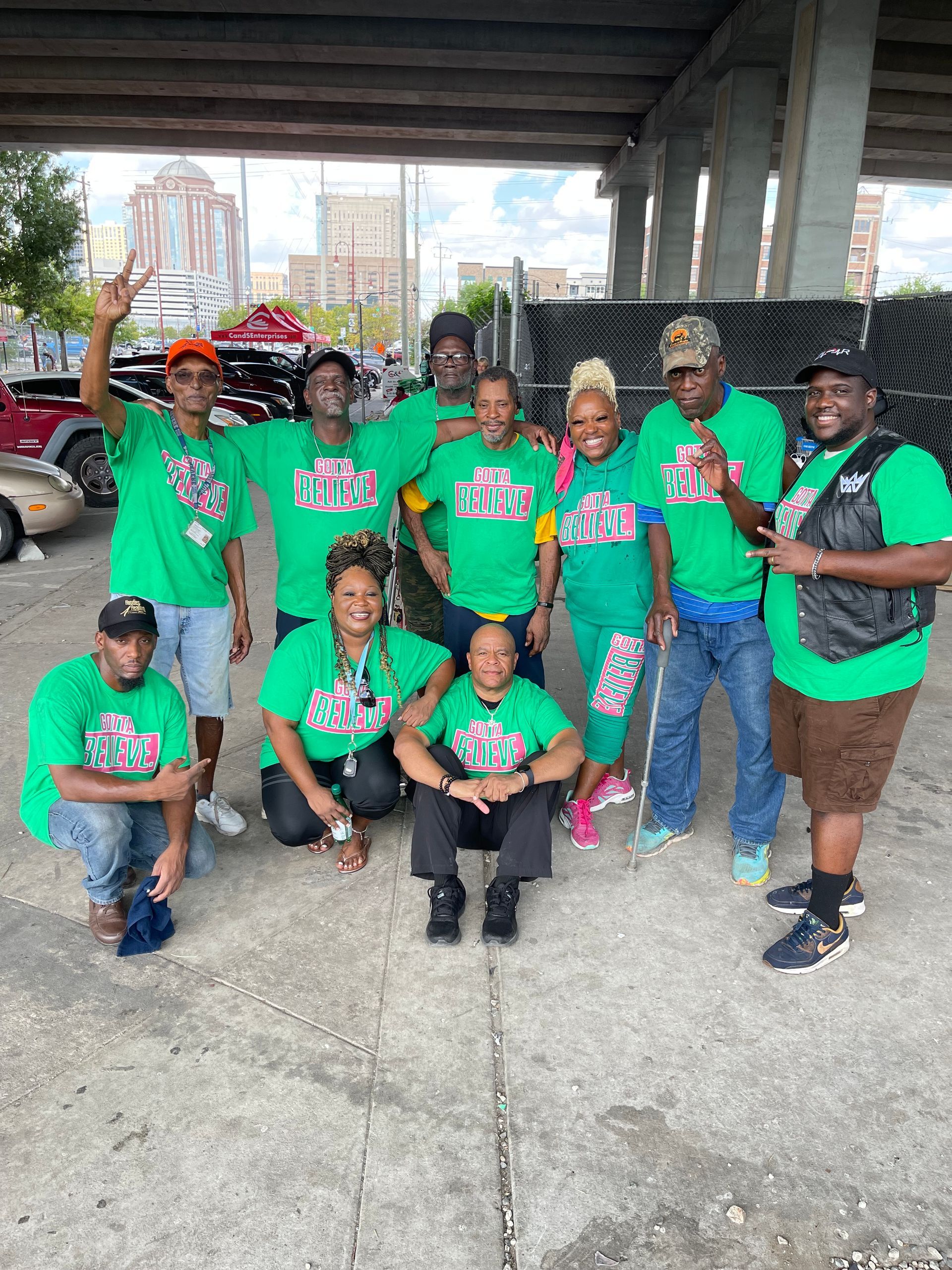 A group of people wearing green shirts are posing for a picture.
