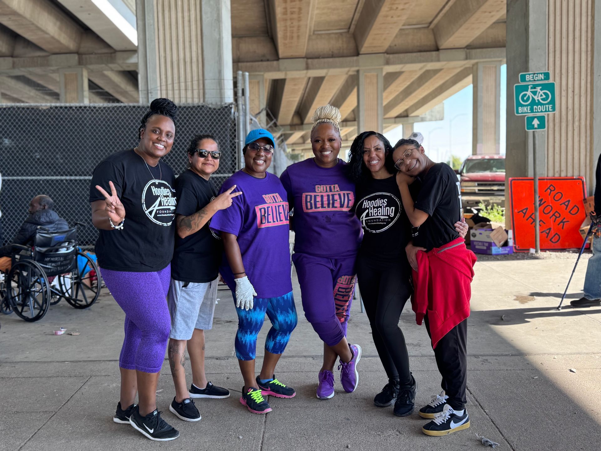 A group of women are posing for a picture under a bridge.