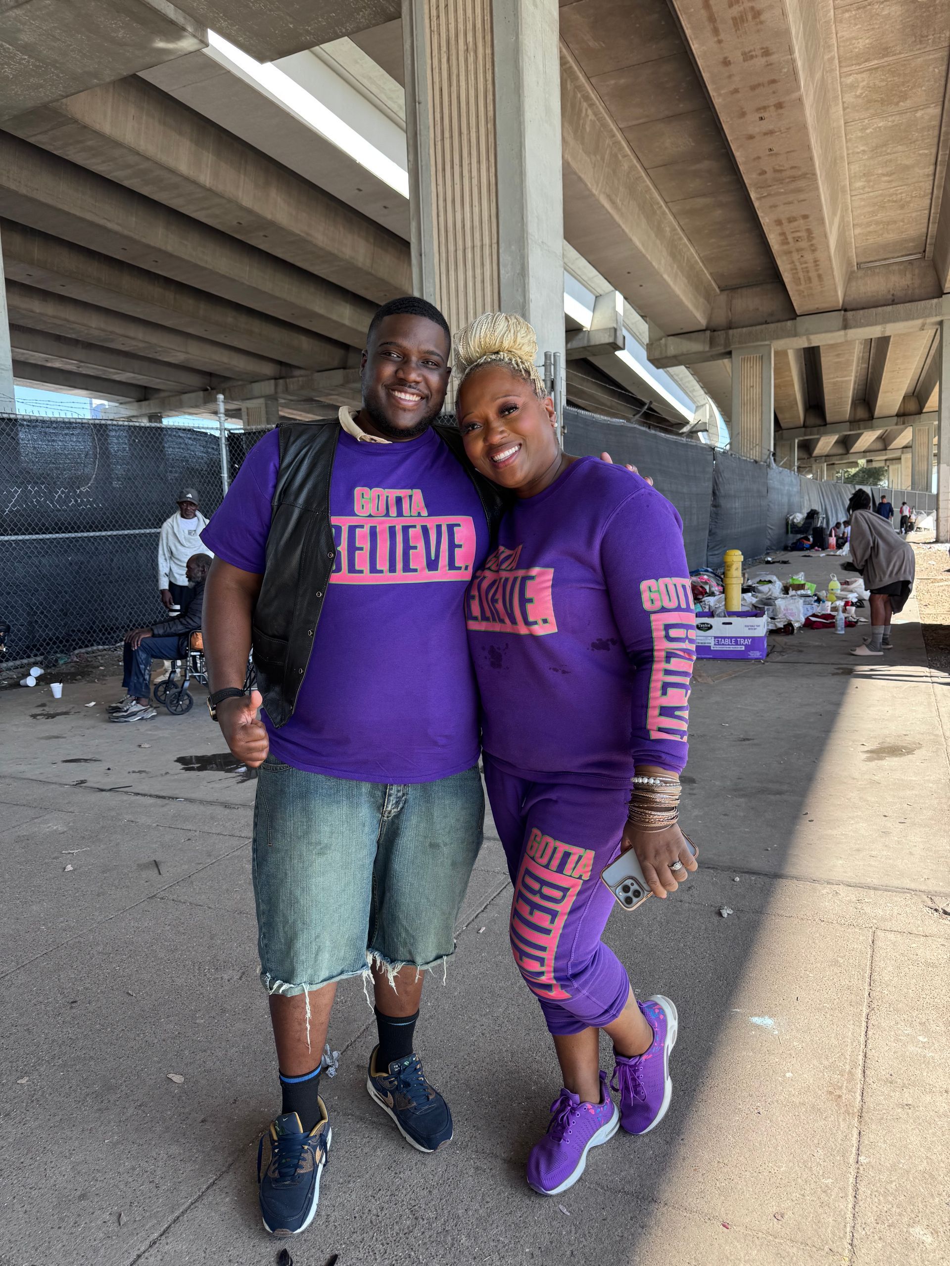 A man and a woman are posing for a picture under a bridge.