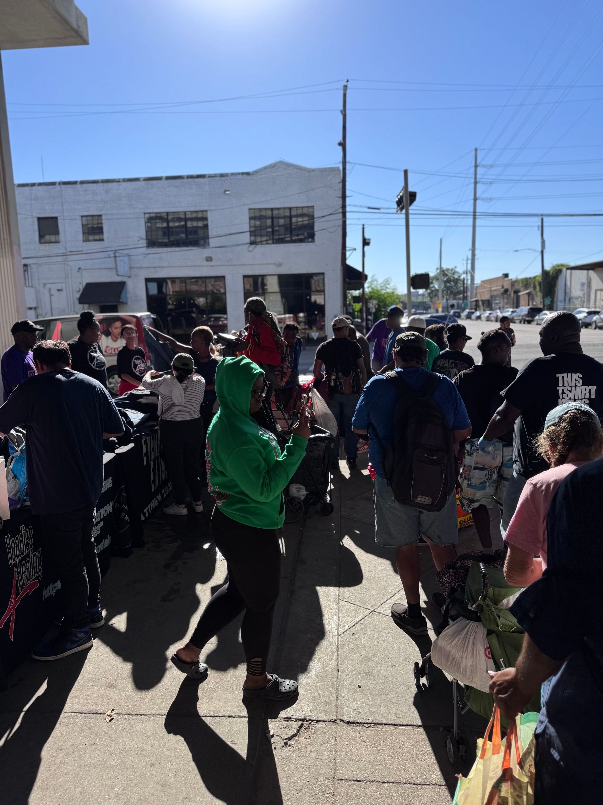 A woman in a green hoodie is standing in a crowd of people