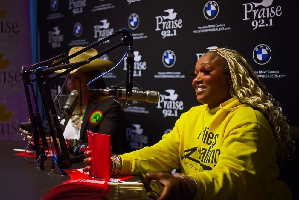 A woman in a yellow shirt is sitting in front of a microphone.