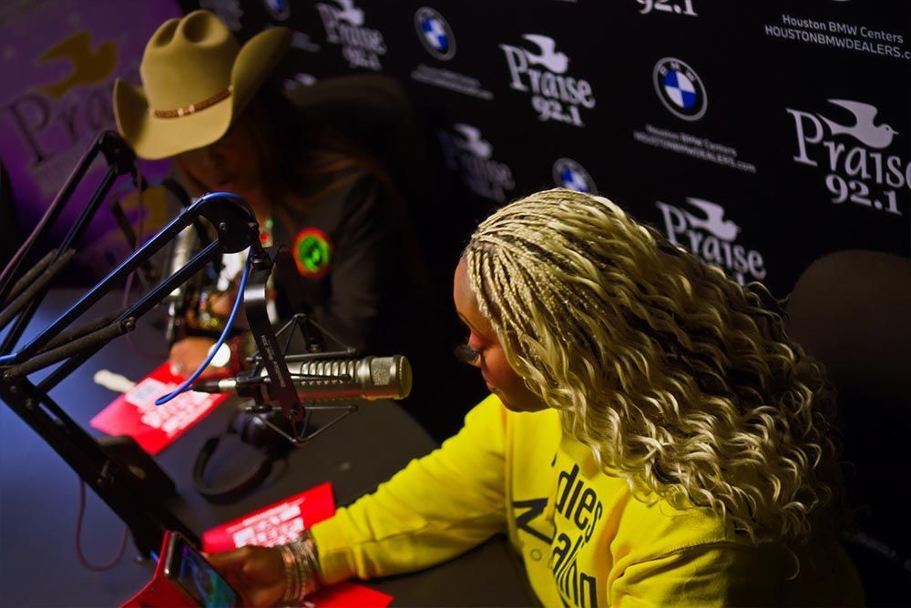 A woman in a yellow sweatshirt is sitting in front of a microphone.