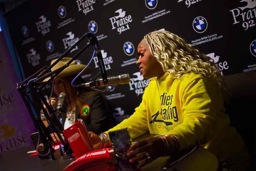 A woman in a yellow shirt is sitting in front of a microphone.
