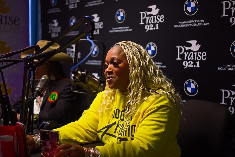 A woman in a yellow shirt is sitting in front of a microphone.