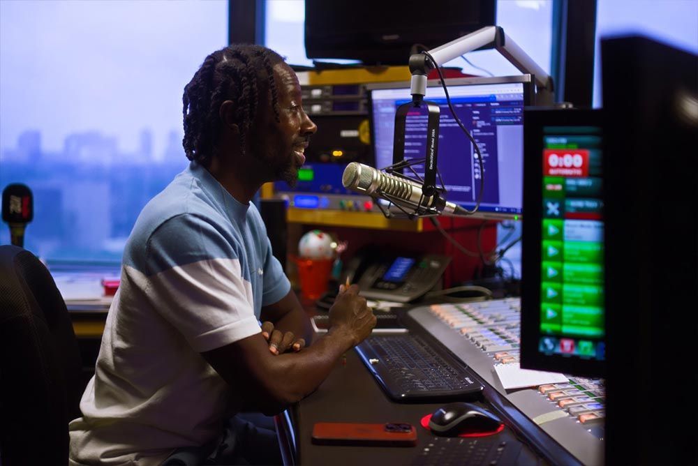 A man is sitting at a desk talking into a microphone