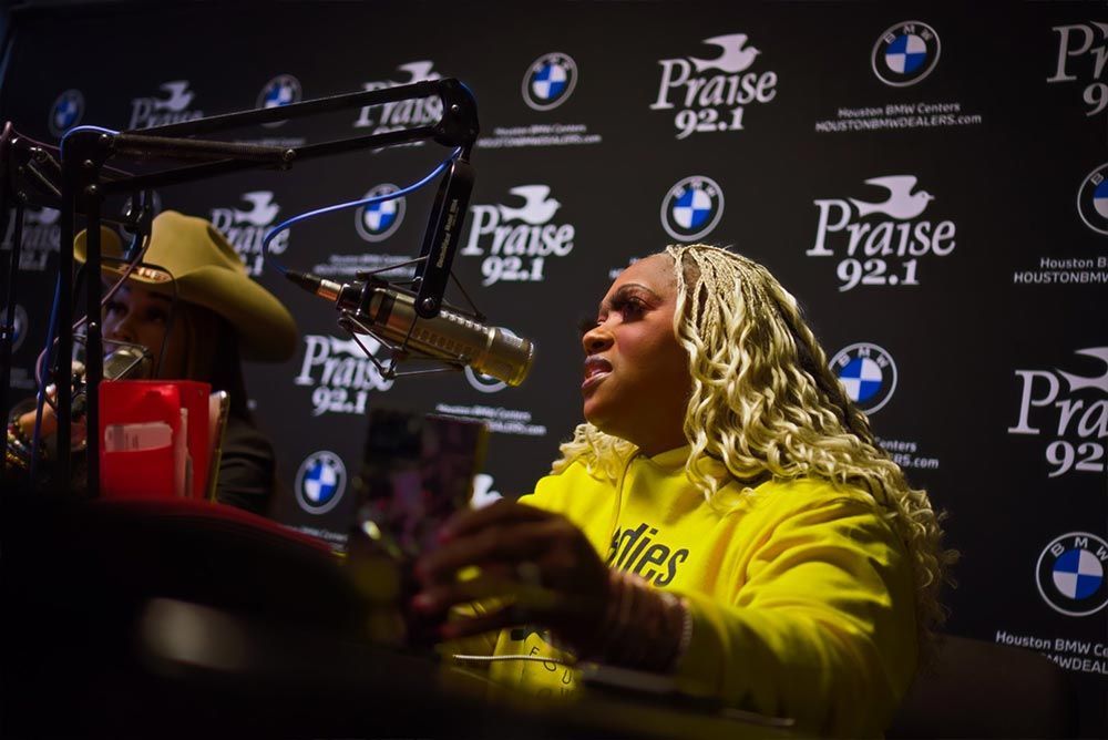 A woman in a yellow shirt is sitting in front of a microphone.