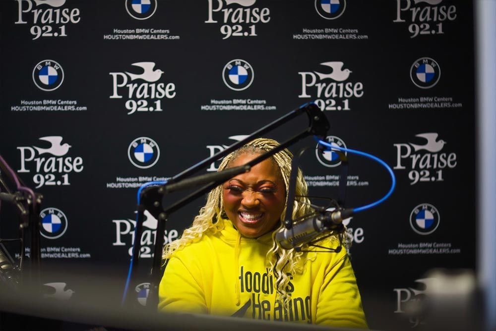A woman in a yellow shirt is sitting in front of a microphone.