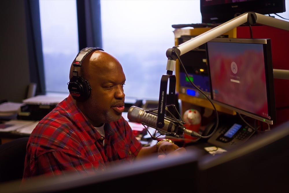 A man wearing headphones is sitting in front of a microphone.