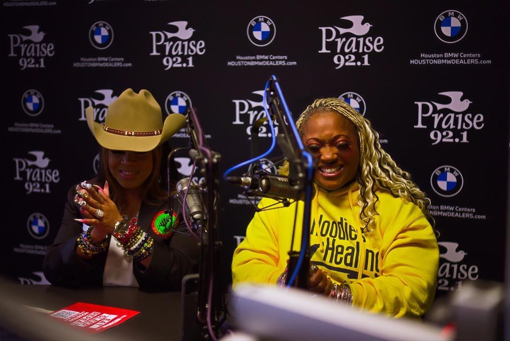 Two women are sitting in front of a microphone at praise 92.1