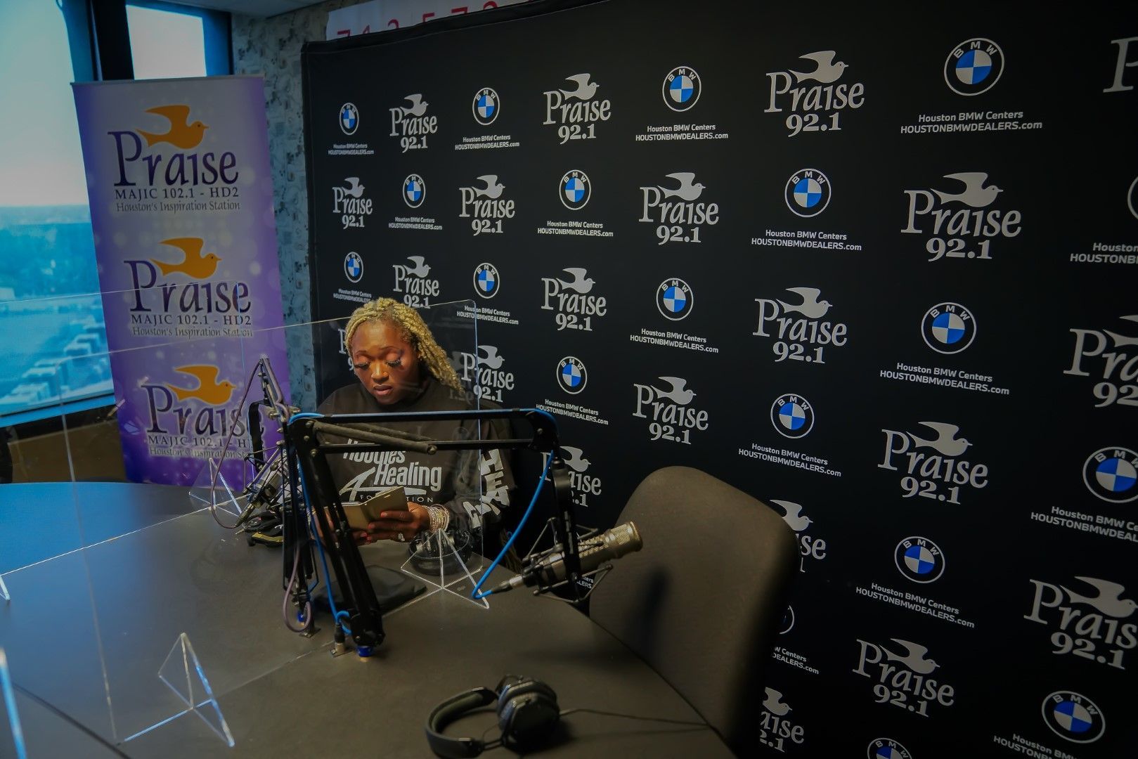 A man is sitting in front of a microphone in a radio studio.