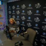 A man is sitting at a table in front of a microphone in a studio.