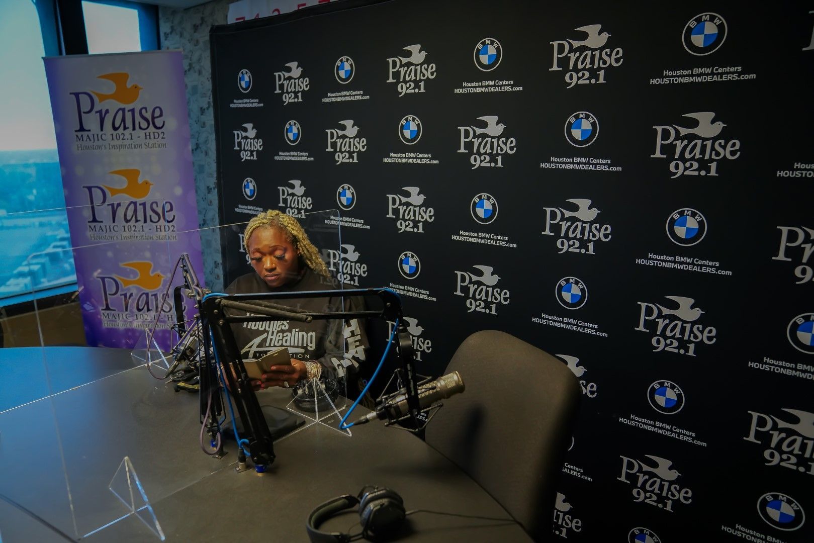 A woman is sitting in front of a microphone in a radio studio.