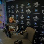 A man in a wheelchair is sitting in front of a microphone in a room.