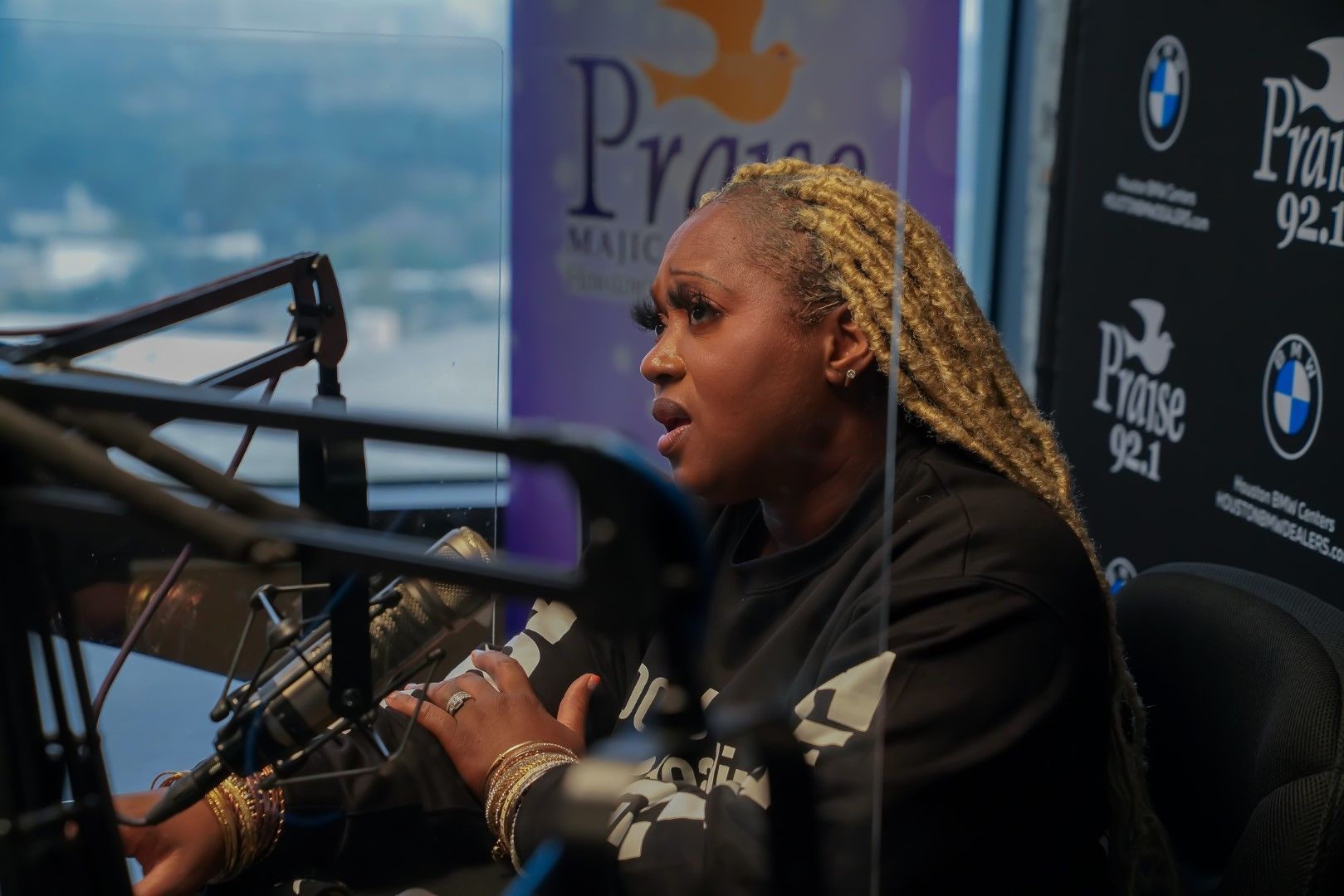 A woman is sitting in front of a microphone in a studio.