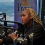 A woman is sitting in front of a microphone in a radio studio.