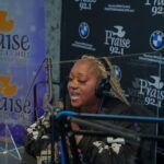 A woman is singing into a microphone in a radio studio.