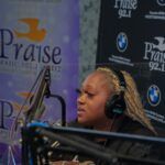 A woman wearing headphones is sitting in front of a microphone.