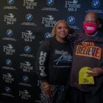 A man and a woman wearing masks are standing next to each other in front of a wall.
