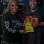 A man and a woman are posing for a picture while holding a trophy.