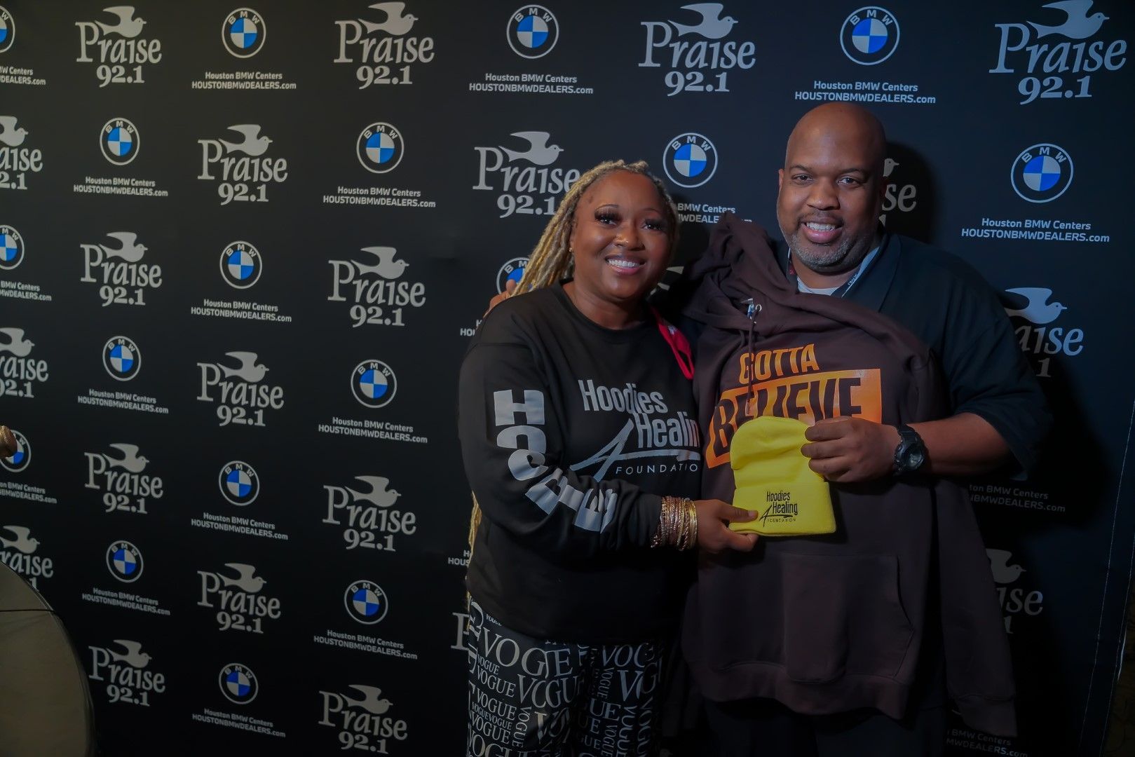 A man and a woman are posing for a picture in front of a wall with bmw logos.
