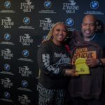 A man and a woman are posing for a picture in front of a wall.