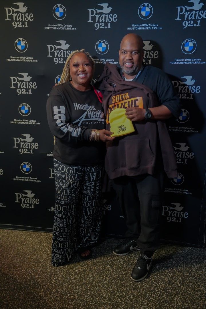 A man and a woman are posing for a picture in front of a wall with bmw logos.
