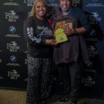 A man and a woman are standing next to each other holding a trophy.