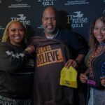 A man and two women are standing next to each other holding a t-shirt that says `` gotta believe ''.