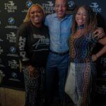 A man and two women are posing for a picture in front of a wall.