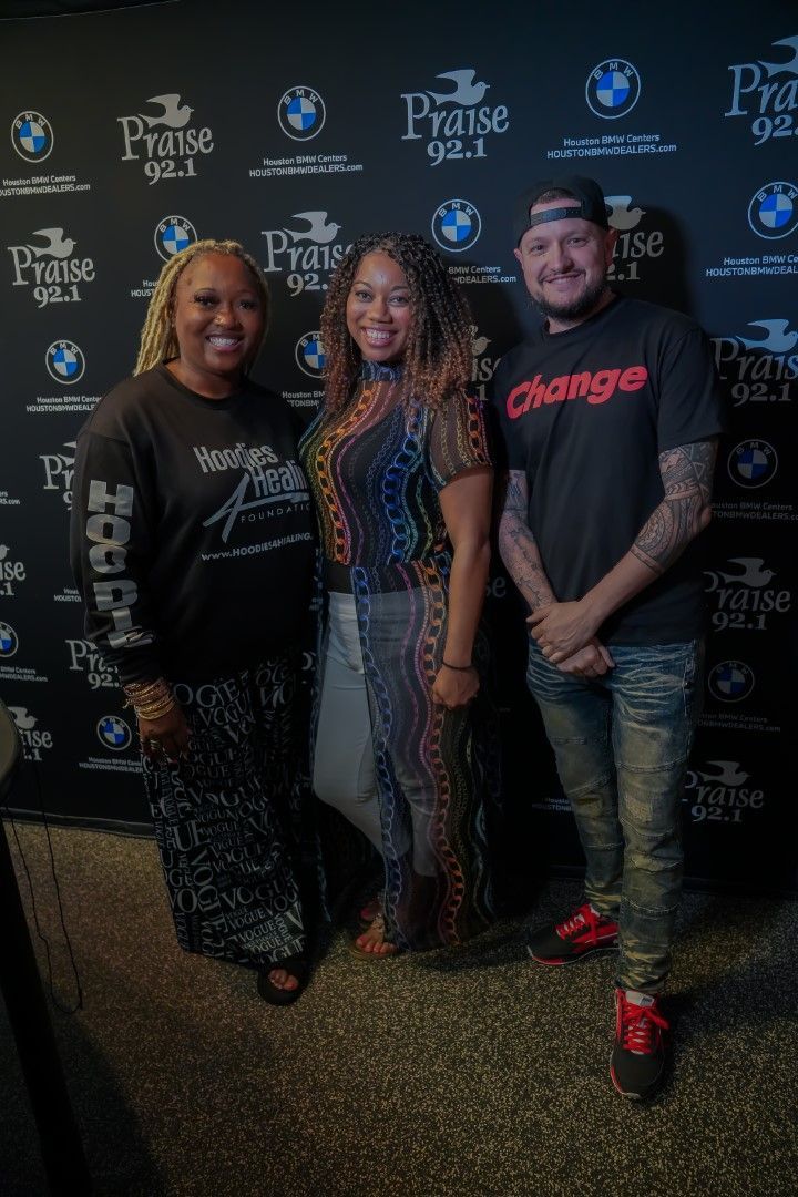 Three people are standing next to each other in front of a wall.