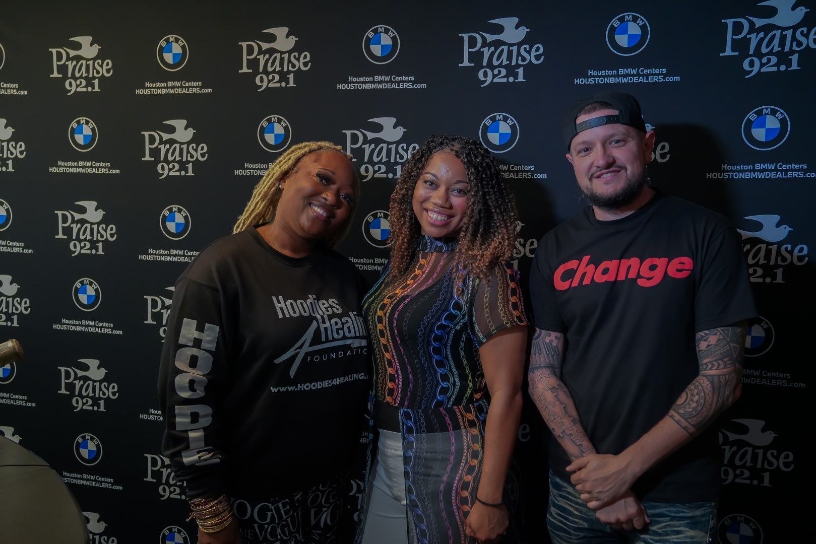 A group of people are posing for a picture in front of a wall with bmw logos on it.