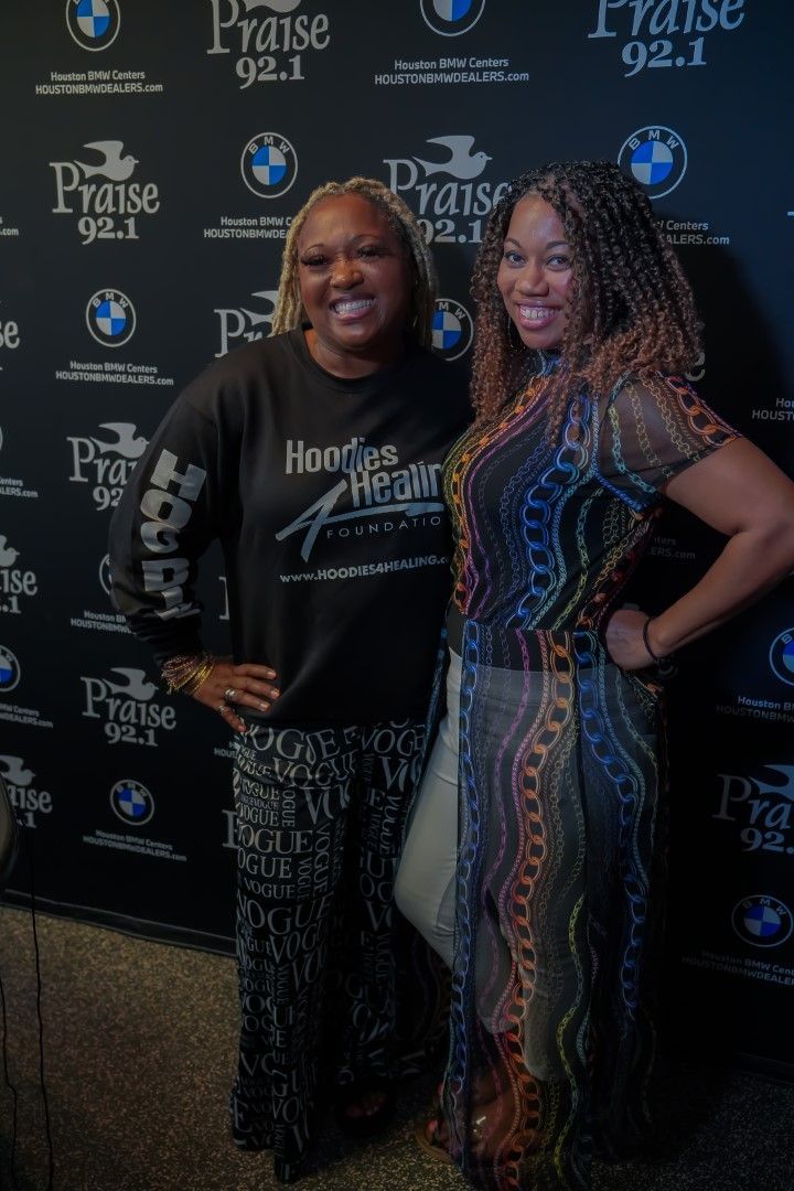 Two women are posing for a picture in front of a wall with bmw logos.