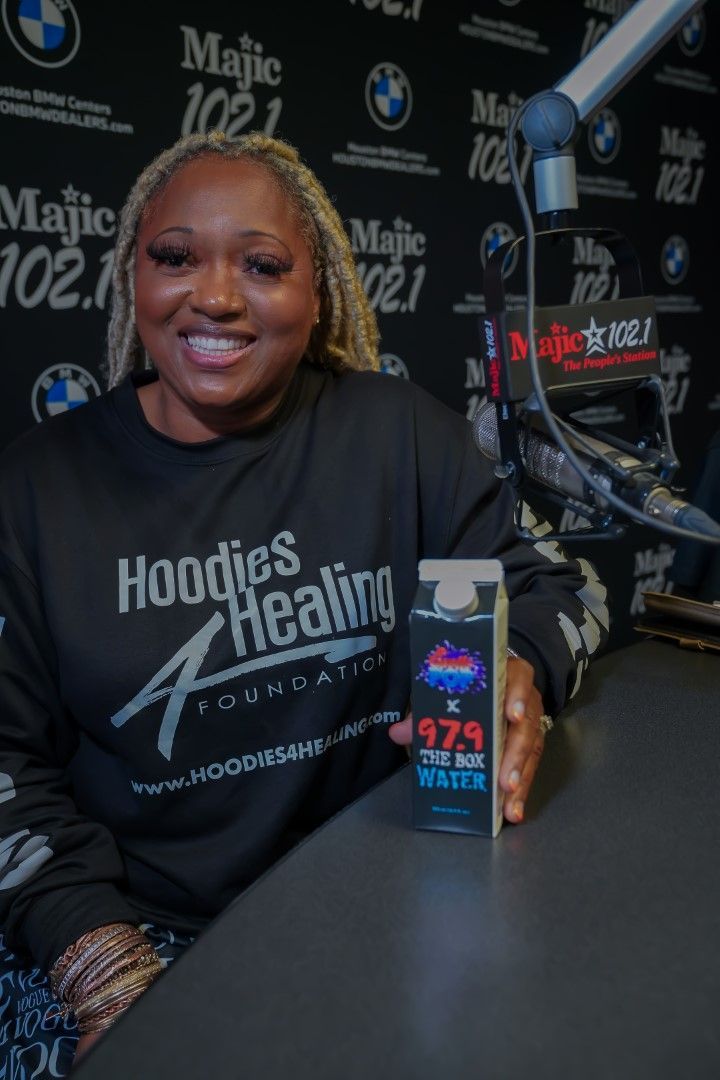 A woman in a hoodie is sitting at a table holding a box of milk.