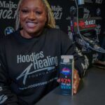 A woman is sitting at a table holding a bottle of pepsi.