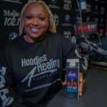 A woman is sitting at a table in front of a microphone holding a cell phone.