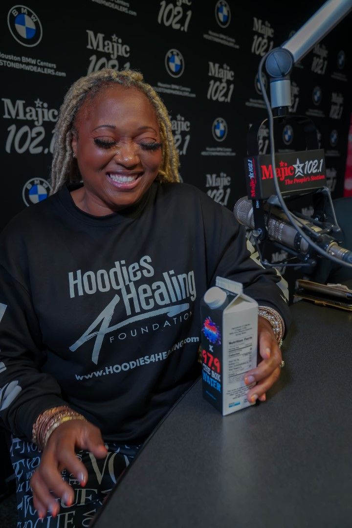 A woman wearing a hoodie holding a carton of milk
