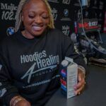 A woman is sitting at a table holding a carton of milk.