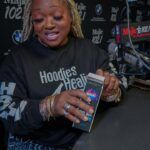 A woman is sitting at a table holding a cell phone.