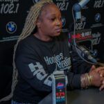 A woman is sitting at a desk in front of a microphone.