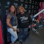 Two women are standing next to each other in front of a microphone in a studio.