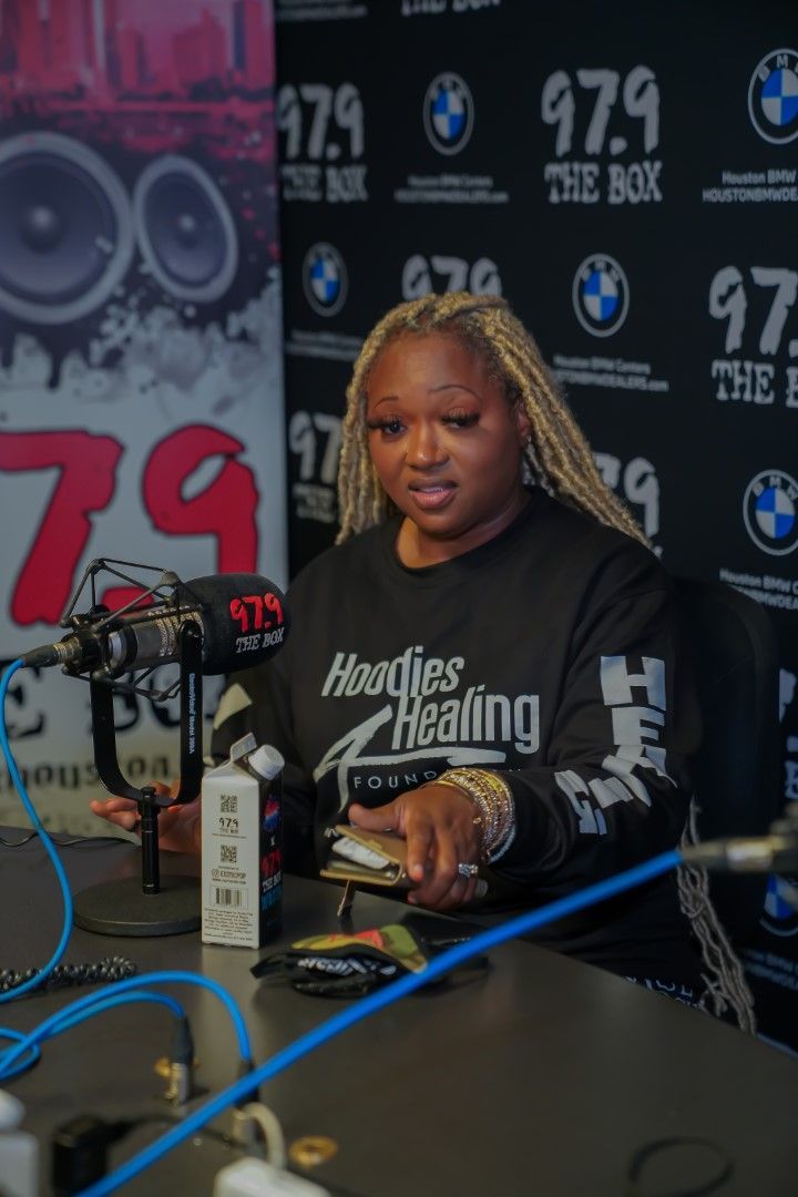 A woman wearing a shirt that says hughes healing is sitting in front of a microphone