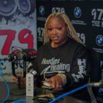 A woman is sitting at a table in front of a microphone in a radio station.
