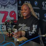 A woman is sitting at a table in front of a microphone.
