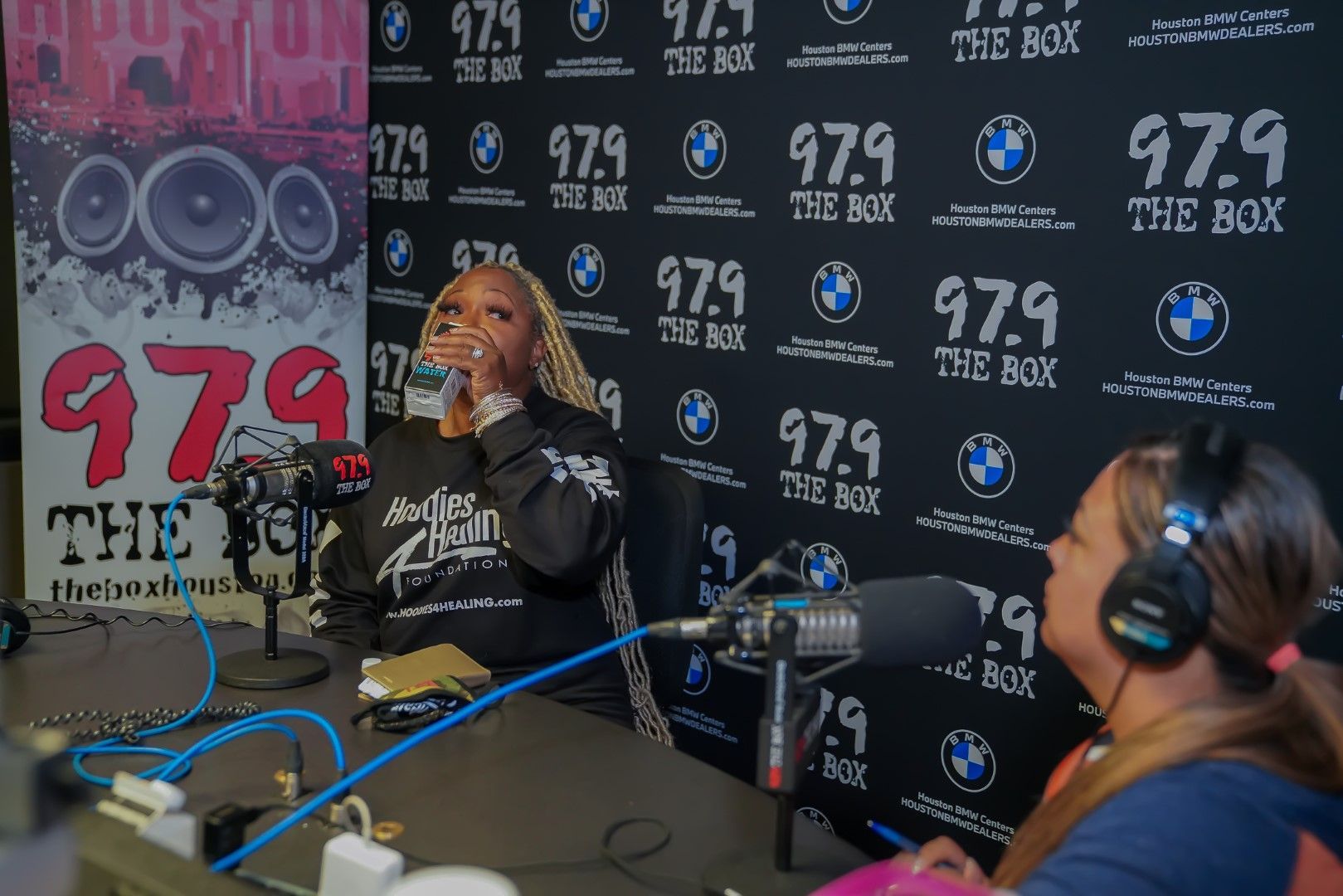 Two women are sitting at a table in front of a microphone.